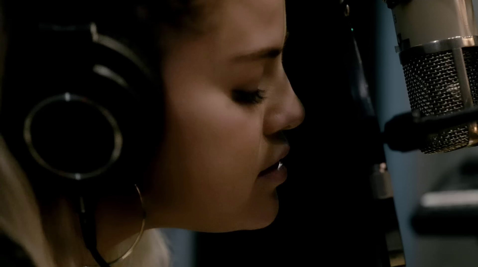 a woman with headphones on singing into a microphone