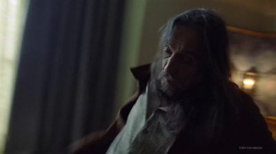 a man with long hair and a beard in a dark room