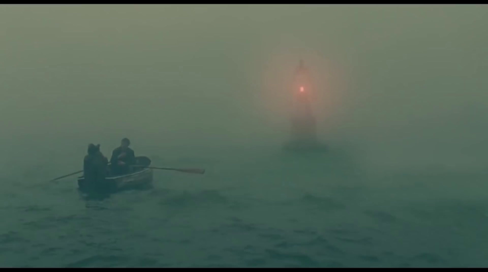 a couple of people in a small boat on a foggy day