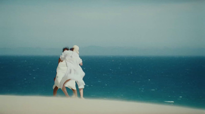 a couple of people standing on top of a sandy beach