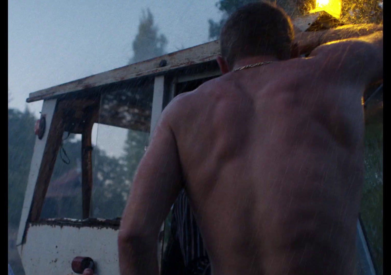 a shirtless man standing in front of a boat