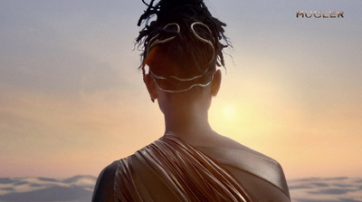 a woman with dreadlocks standing in front of a sunset