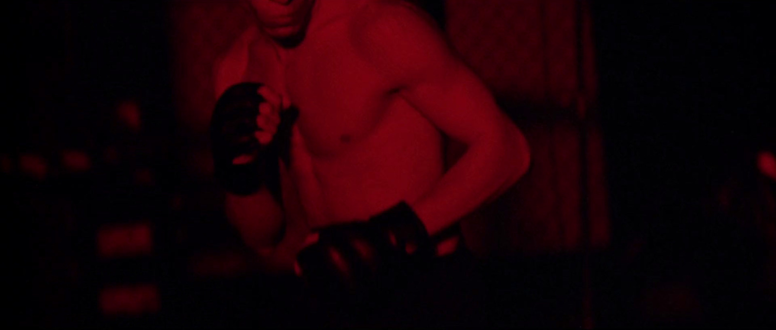 a shirtless man holding a pair of gloves