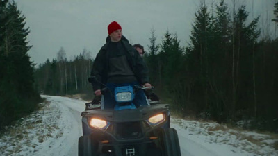 a man riding on the back of an atv down a snow covered road