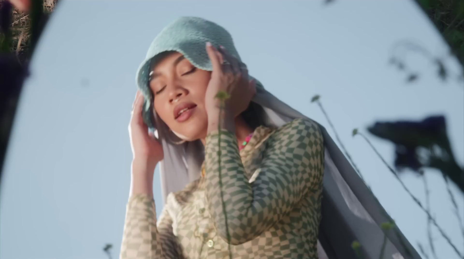 a woman in a green and white dress holding a cell phone to her ear