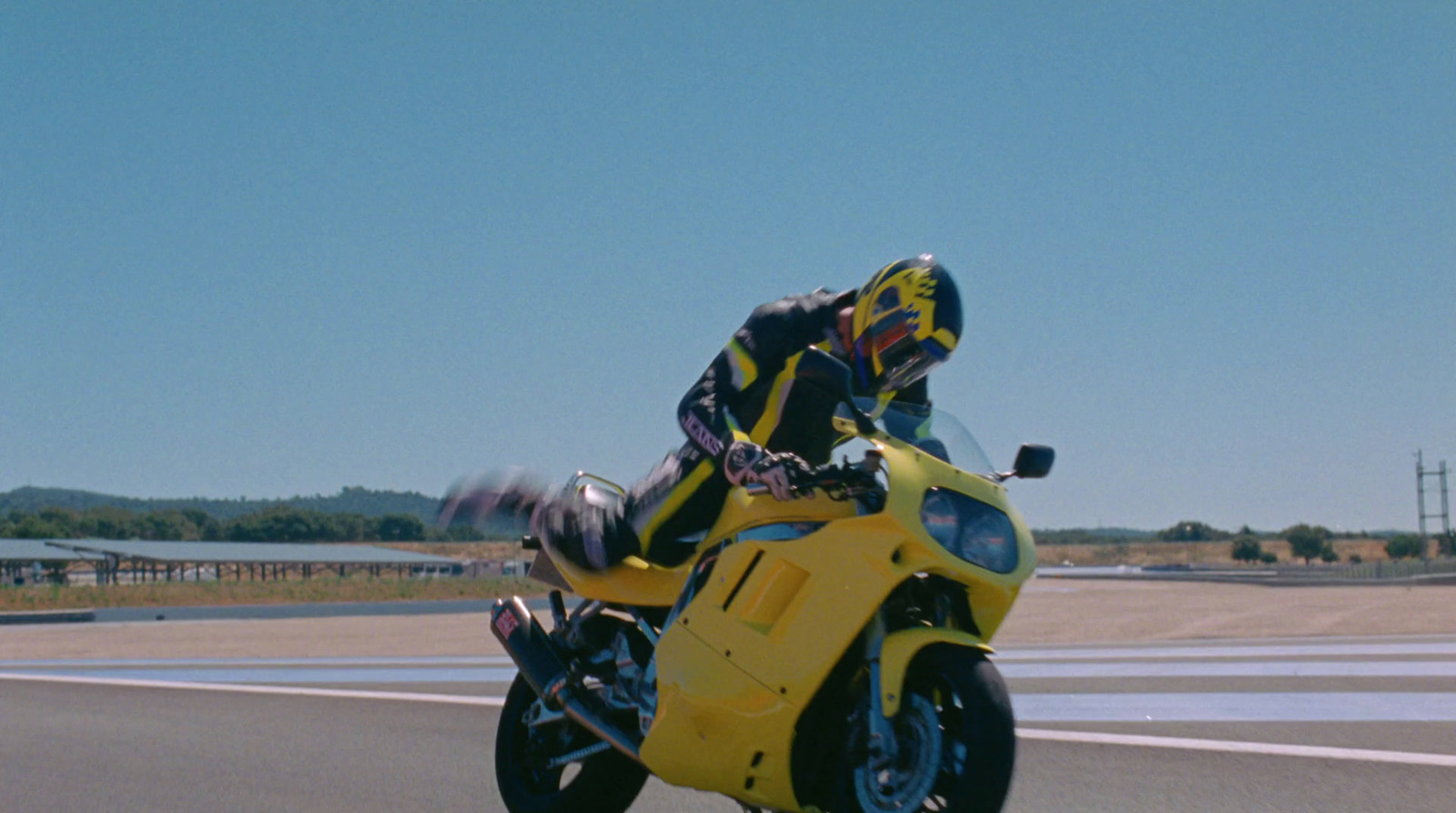 a person riding a yellow motorcycle on a road