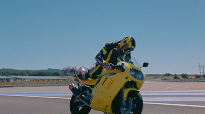 a person riding a yellow motorcycle on a road