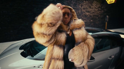 a woman in a fur coat standing next to a car