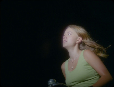 a woman in a green tank top standing in the dark