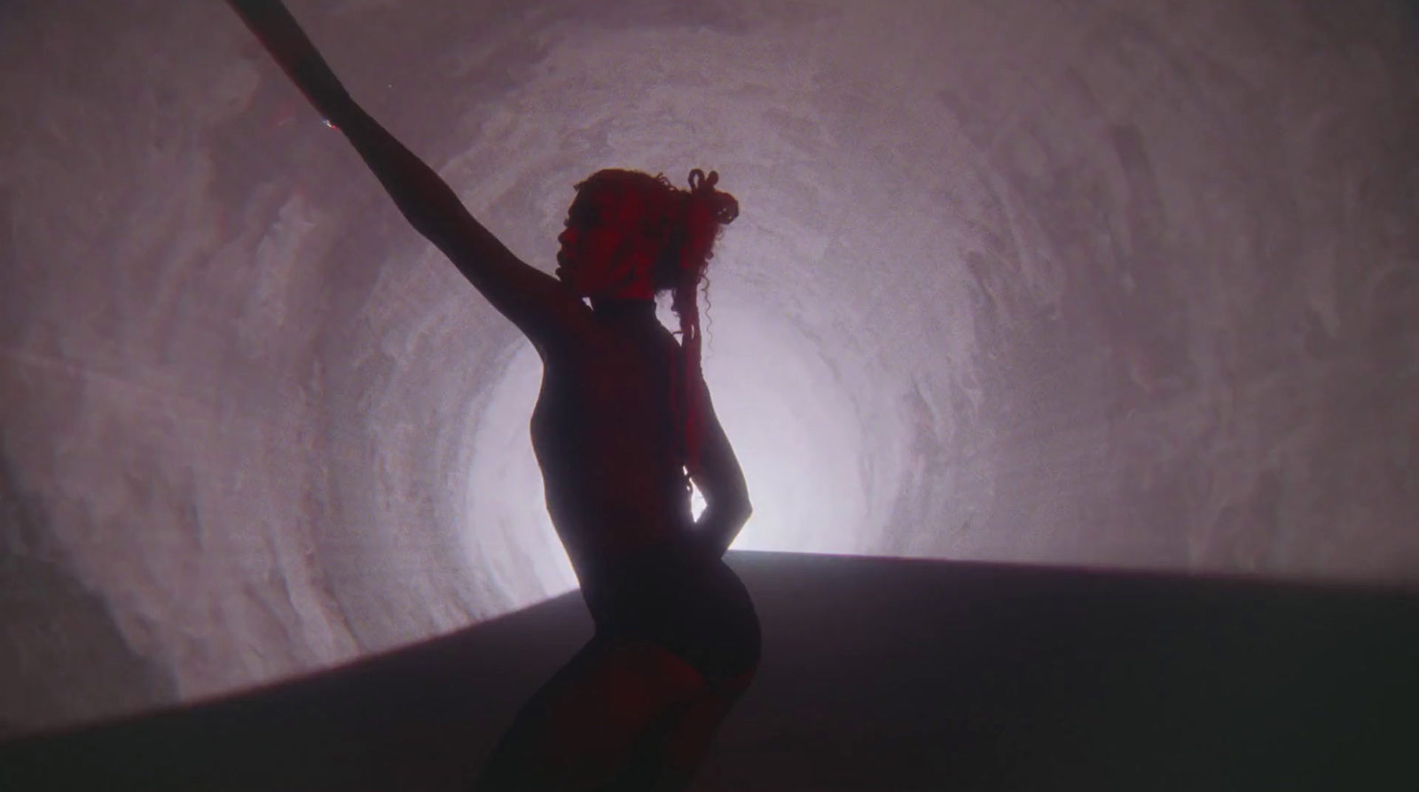 a woman standing in a tunnel with her arms in the air