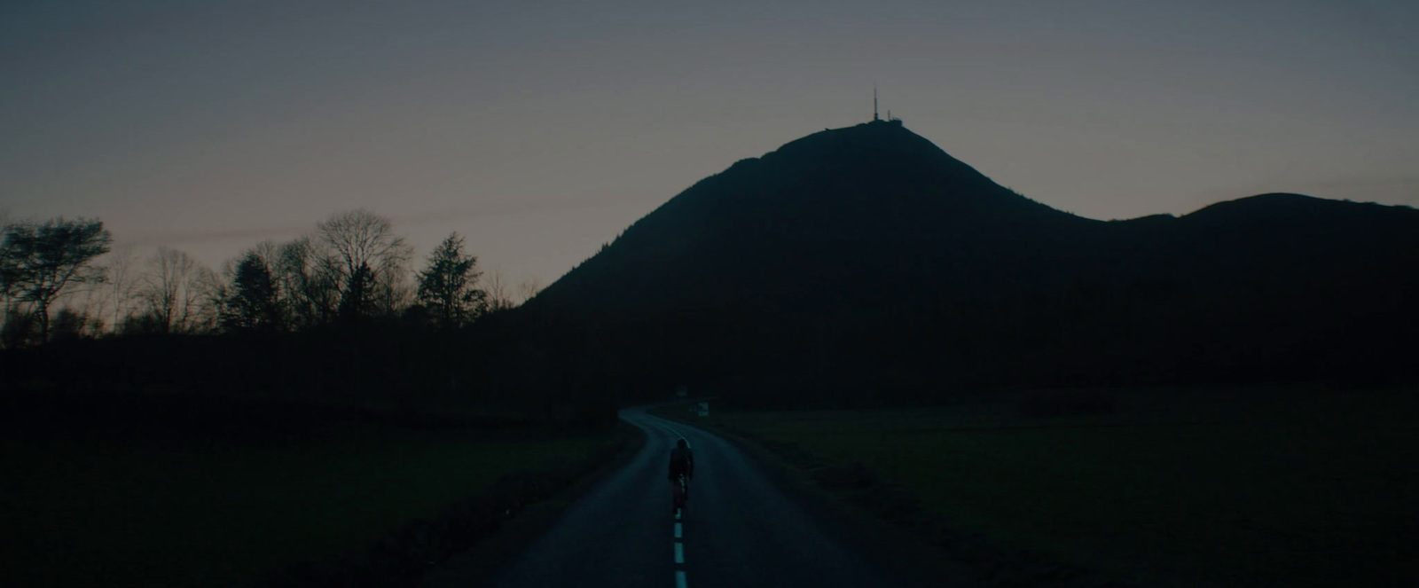 a person riding a bike down a road in the dark