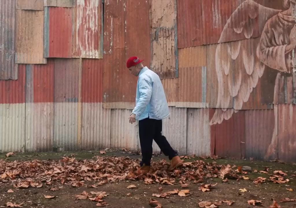 a man walking in front of a wall covered in leaves