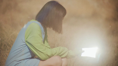 a woman sitting in a field with a laptop