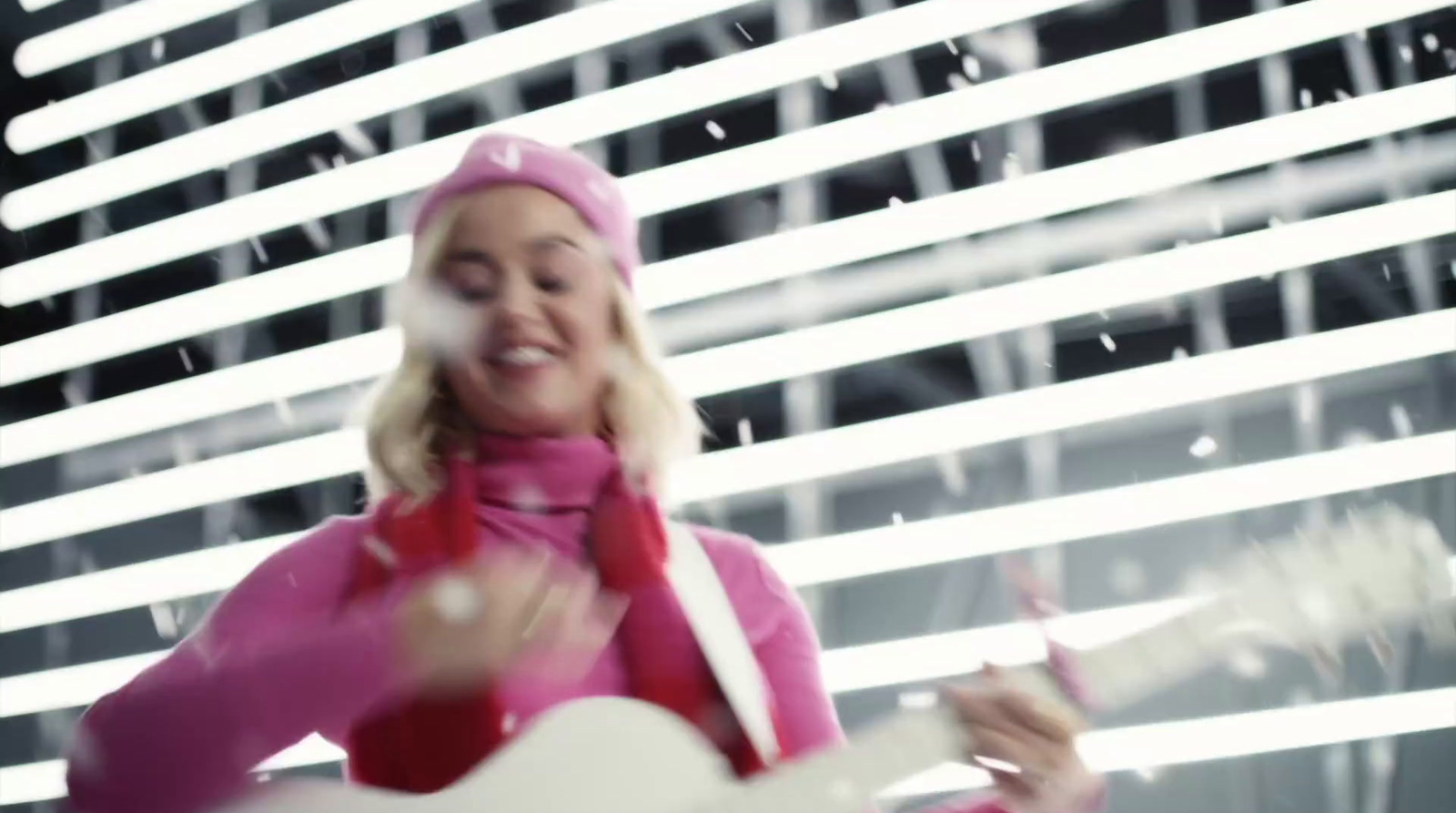 a woman in a pink outfit playing a guitar