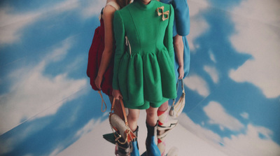 a young girl wearing a green dress and holding a handbag