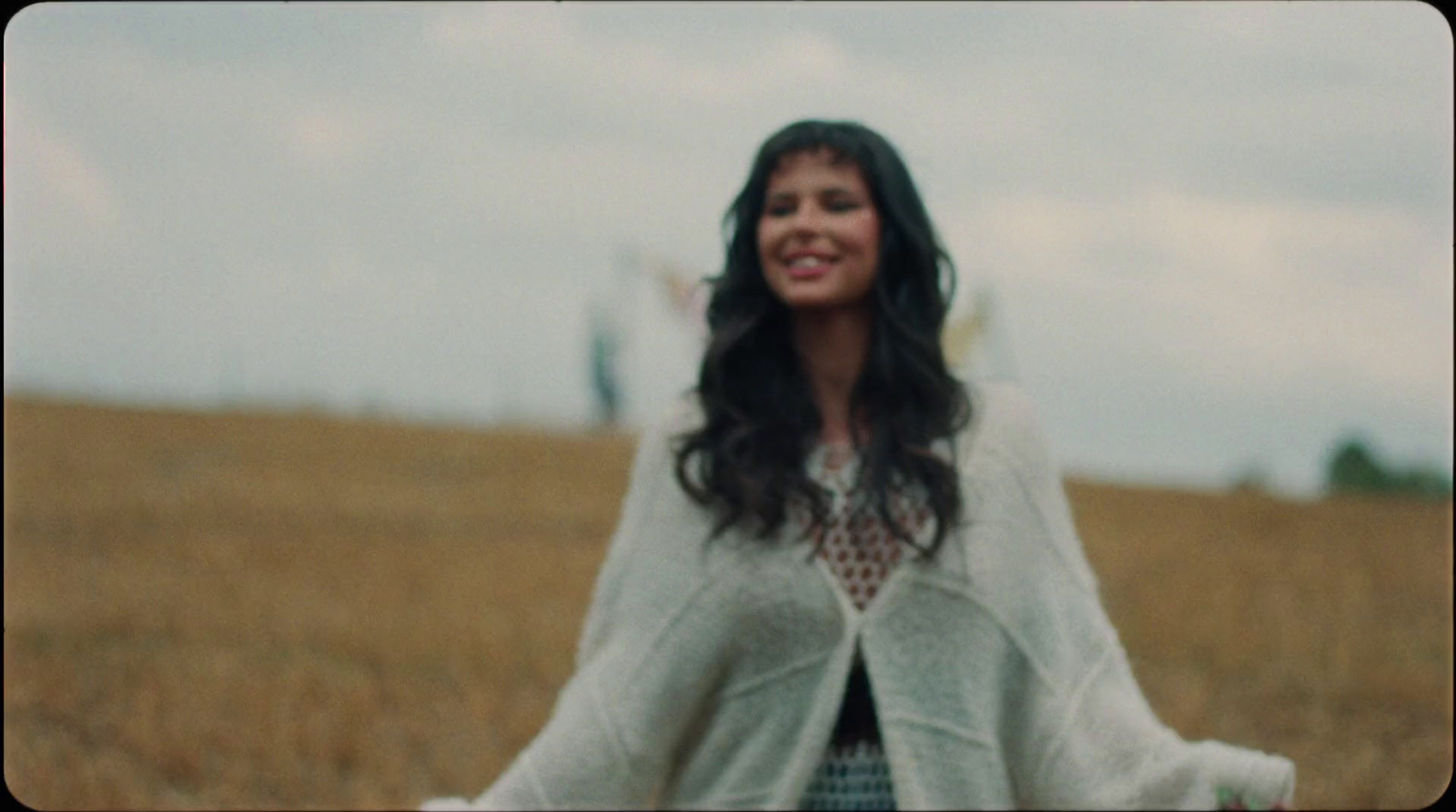 a woman standing in a field with a frisbee in her hand