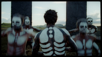 a man with skeleton body paint standing in front of a group of people