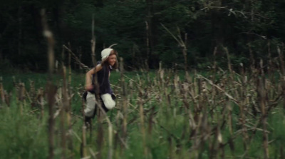 a man walking through a field of tall grass