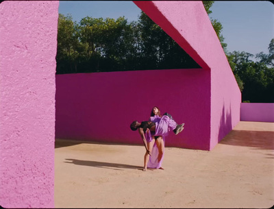 a woman standing in front of a pink wall