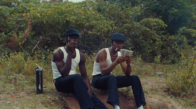 two men sitting on a log in the woods