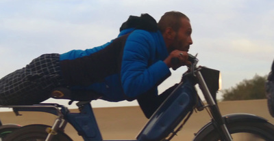 a man riding a blue bike down a street