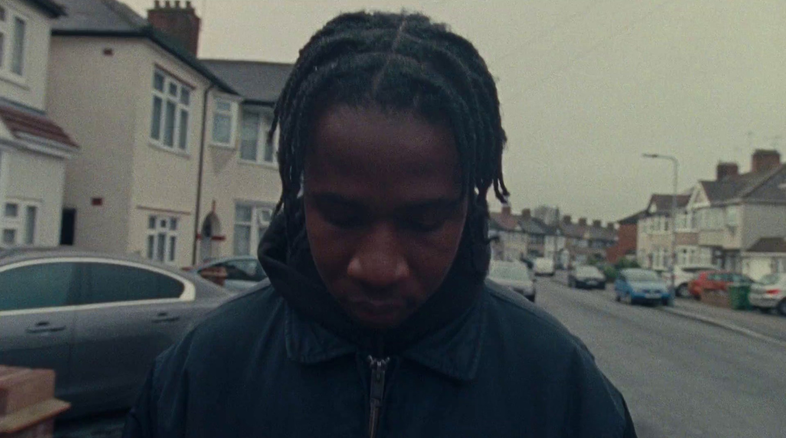 a man with dreadlocks standing in front of a street