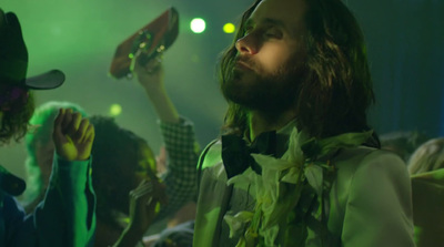 a man with long hair standing next to another man