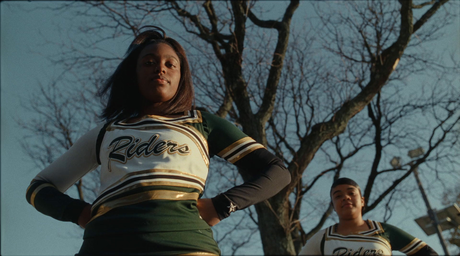 two cheerleaders standing in front of a tree