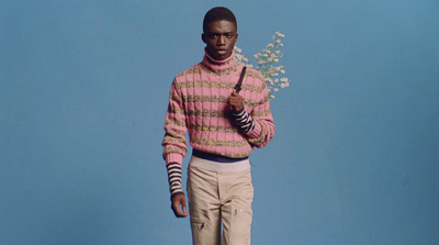 a man in a pink sweater holding a flower