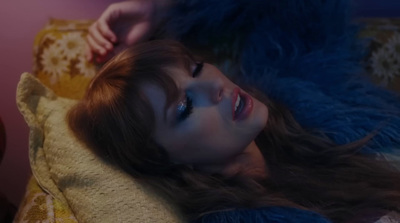 a woman laying on top of a bed next to a blue teddy bear