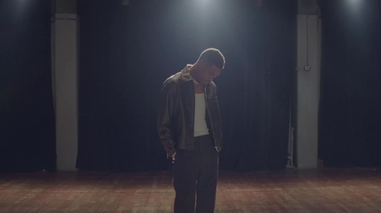 a man standing on a wooden floor in a dark room