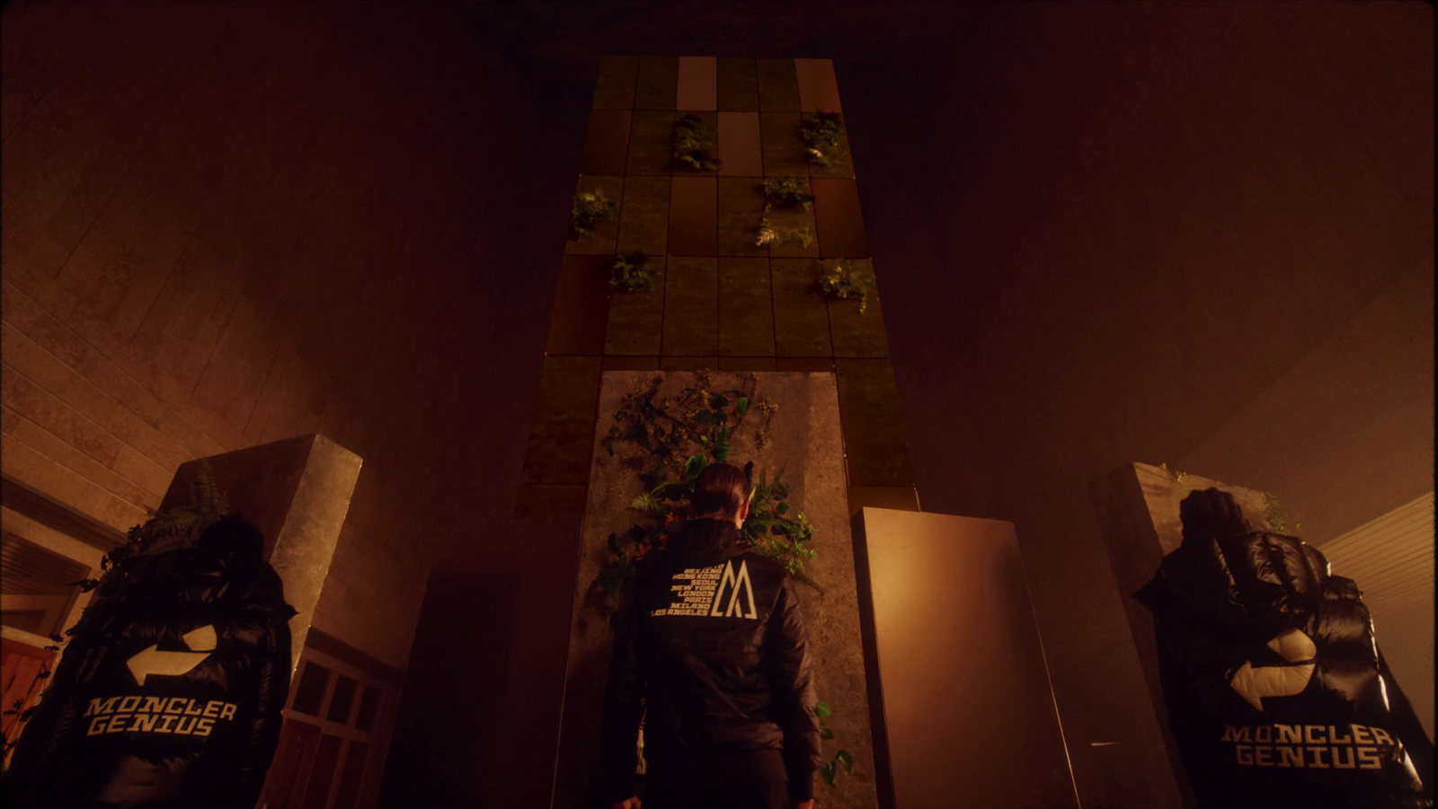 a man standing next to a wall with plants growing on it