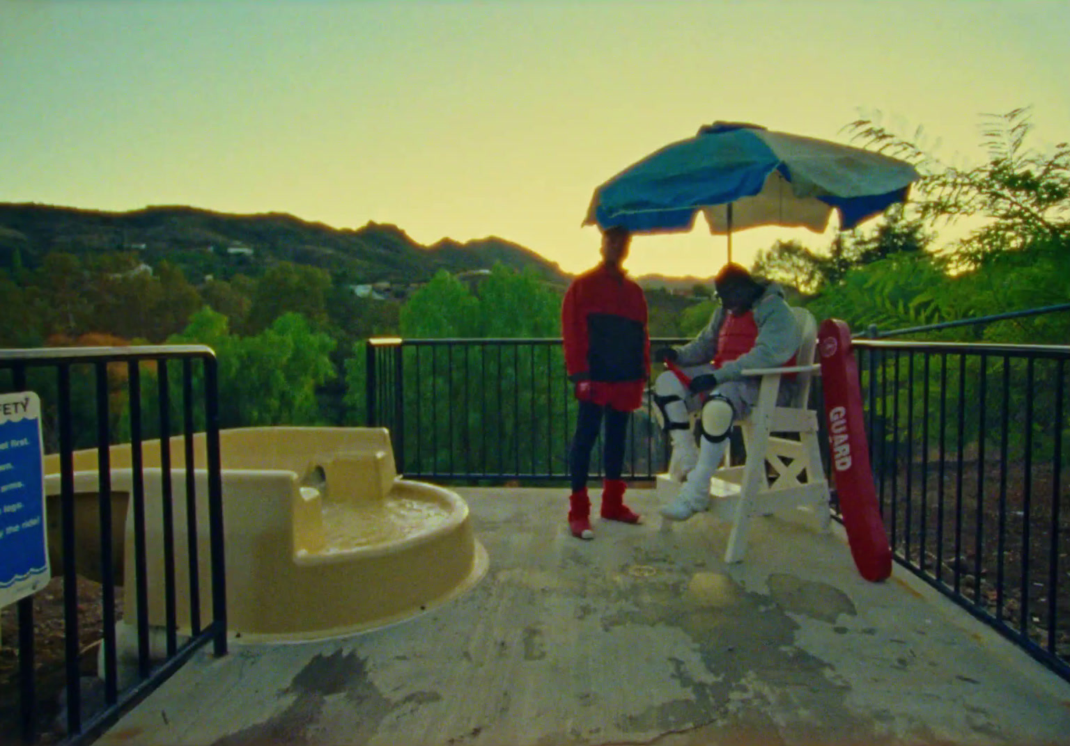 two people sitting on a bench under an umbrella