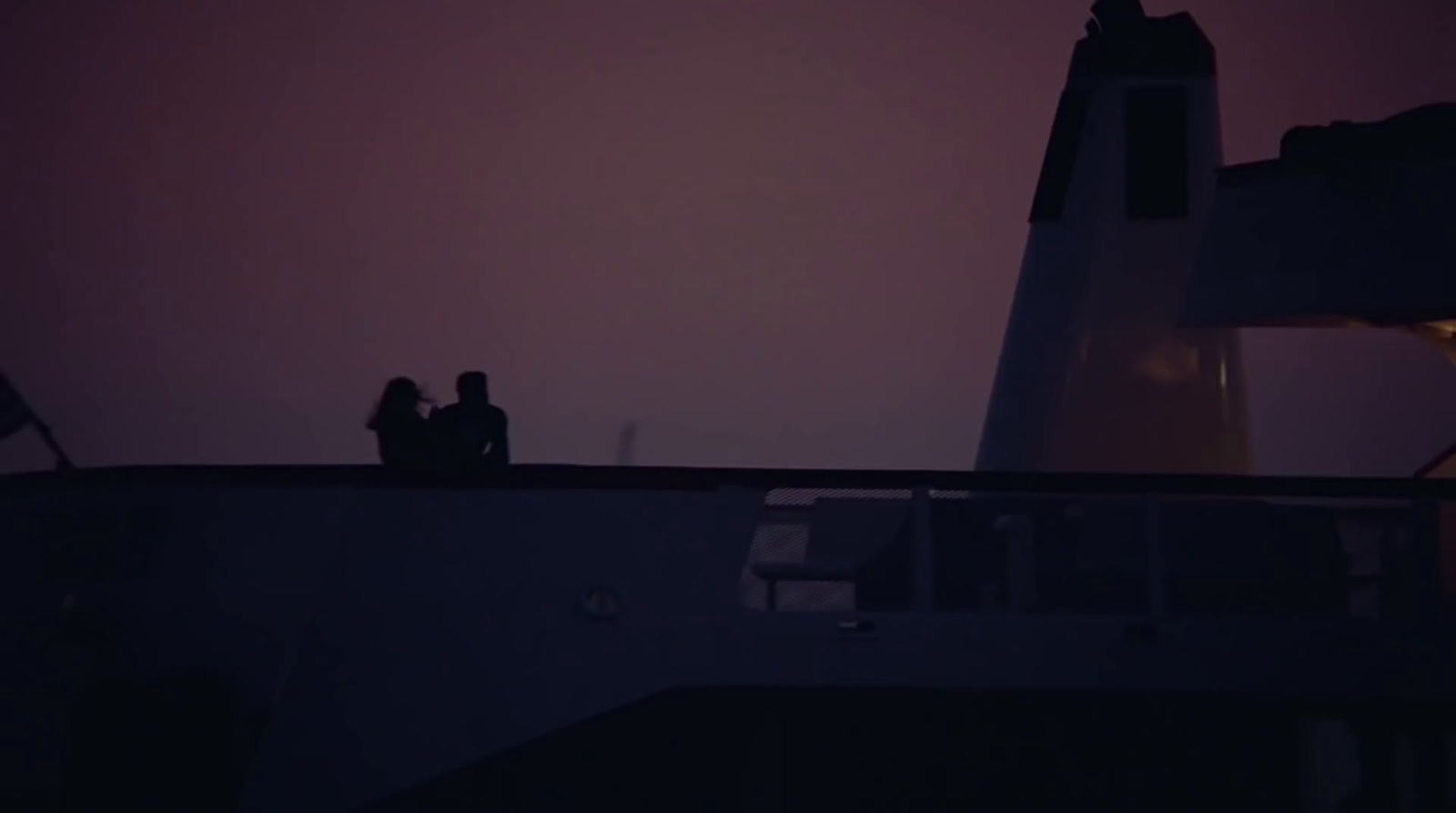 two people sitting on a roof at night