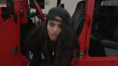 a woman with long hair sitting in a red jeep