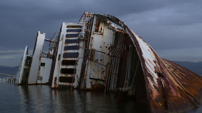 a rusted boat sitting in a body of water