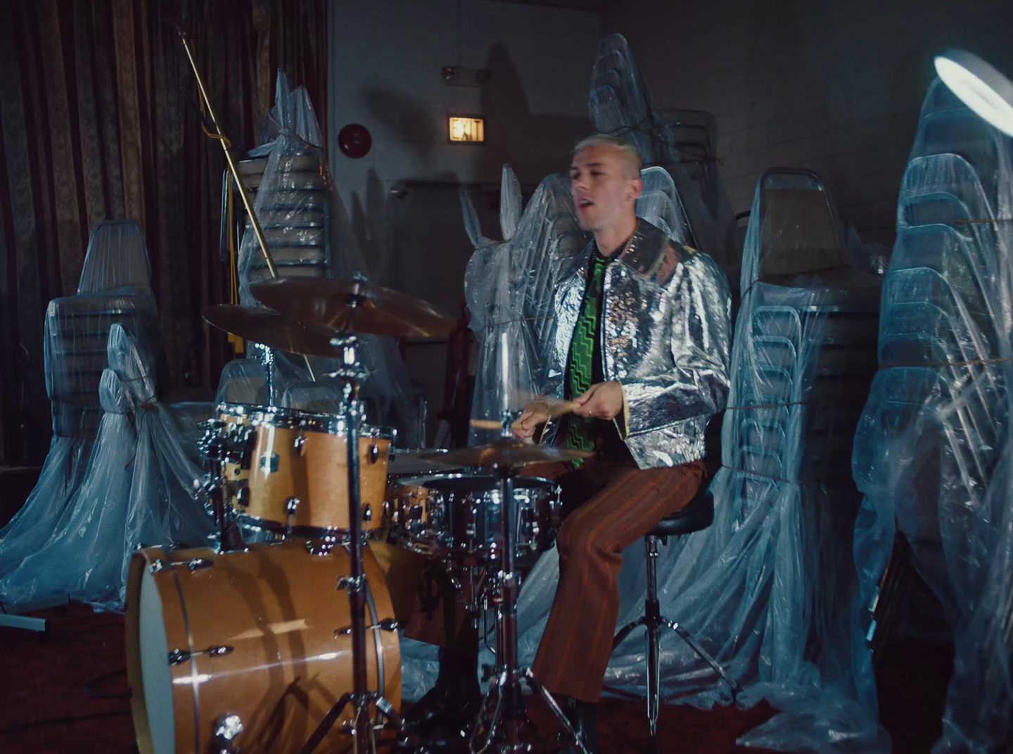 a man sitting on a stool in front of a drum set