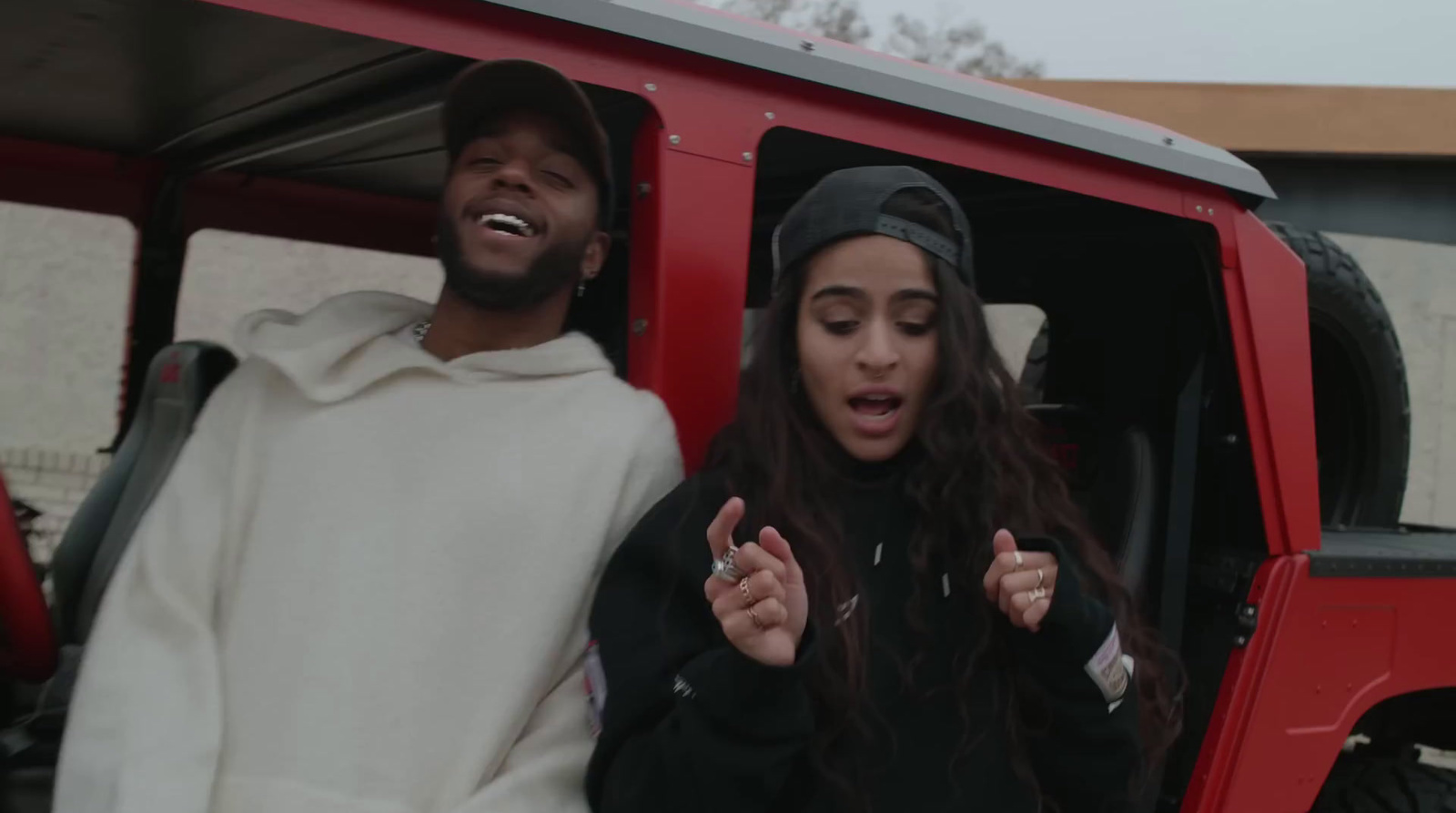 a man and a woman standing in the back of a red truck