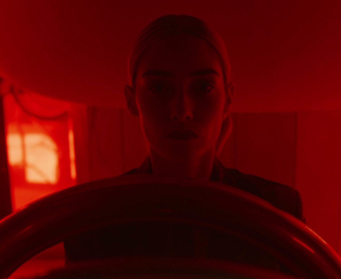 a woman standing behind a steering wheel in a dark room