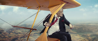 a man in a suit and tie sitting on a biplane