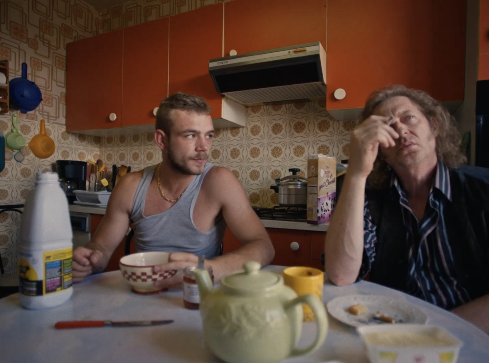 a couple of men sitting at a table in a kitchen