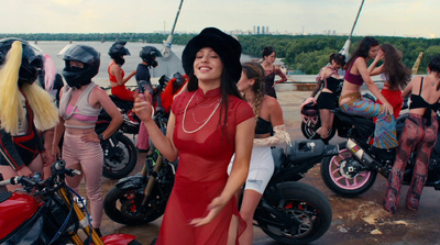 a woman in a red dress standing in front of a group of bikers