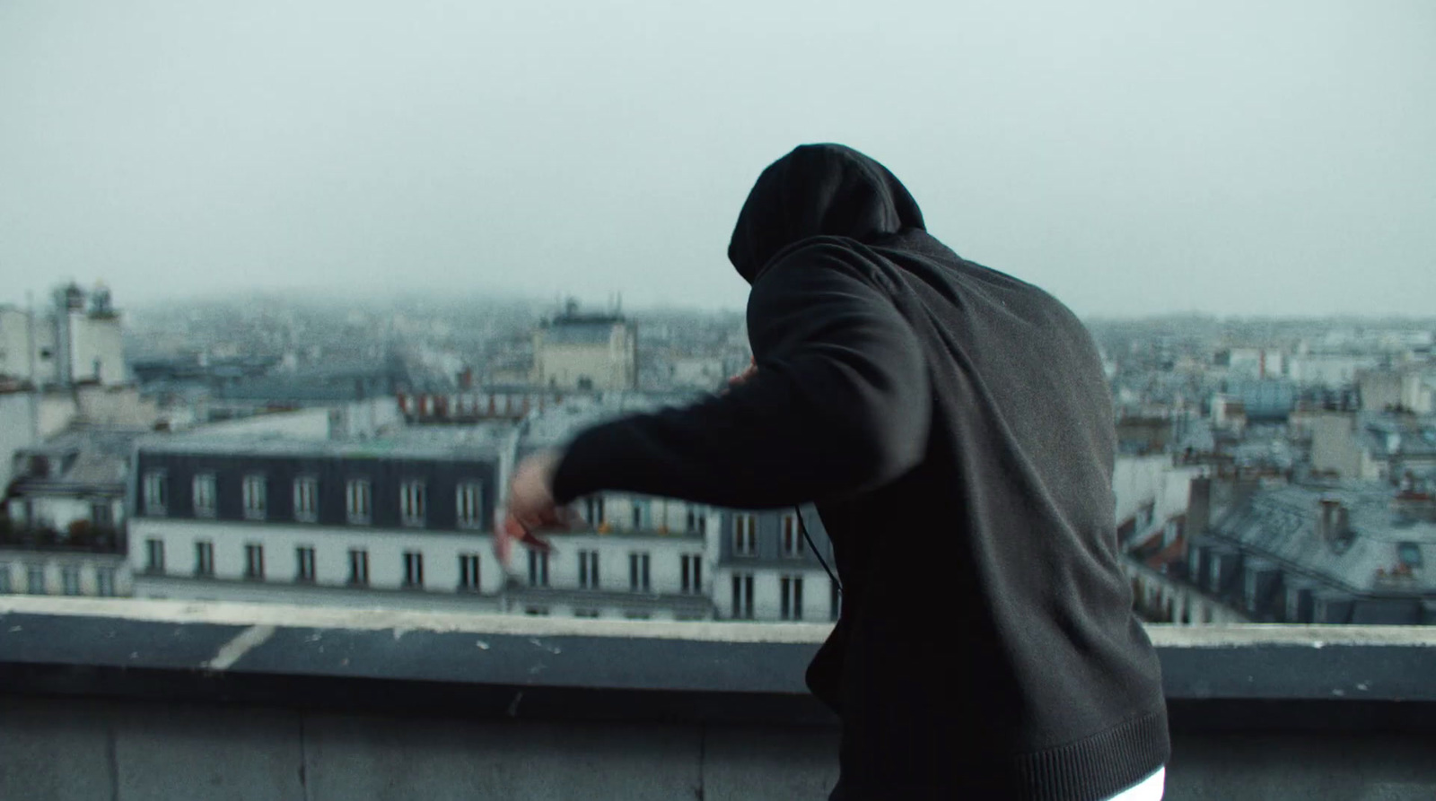 a man in a hoodie standing on top of a building