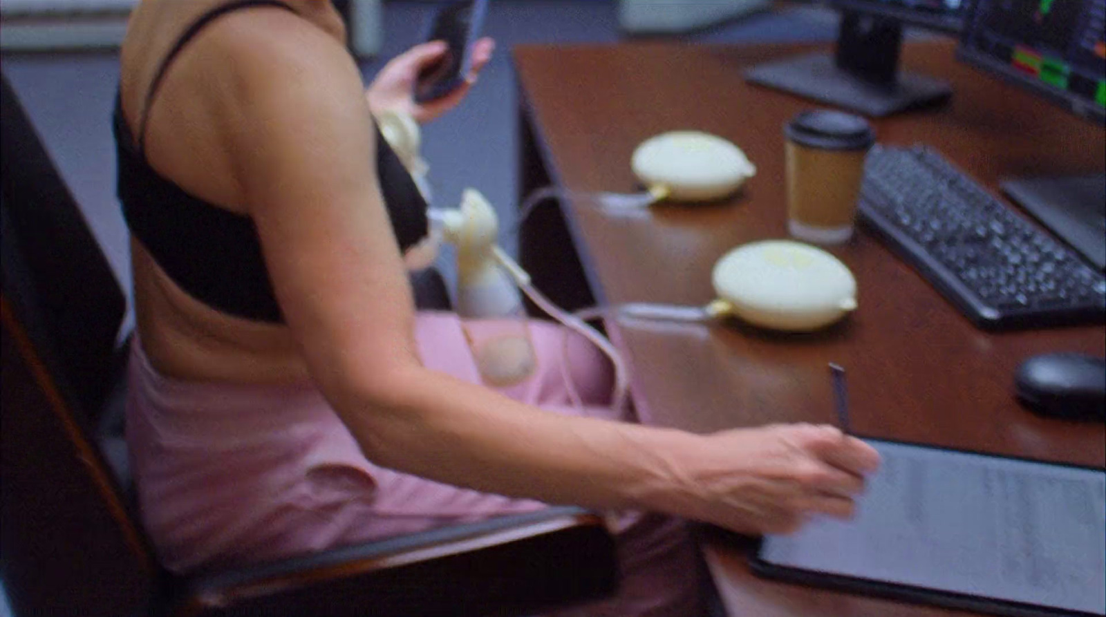 a woman sitting at a desk using a cell phone