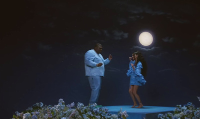 a man and a woman standing on a stage in front of a full moon