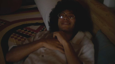 a man laying in bed wearing glasses