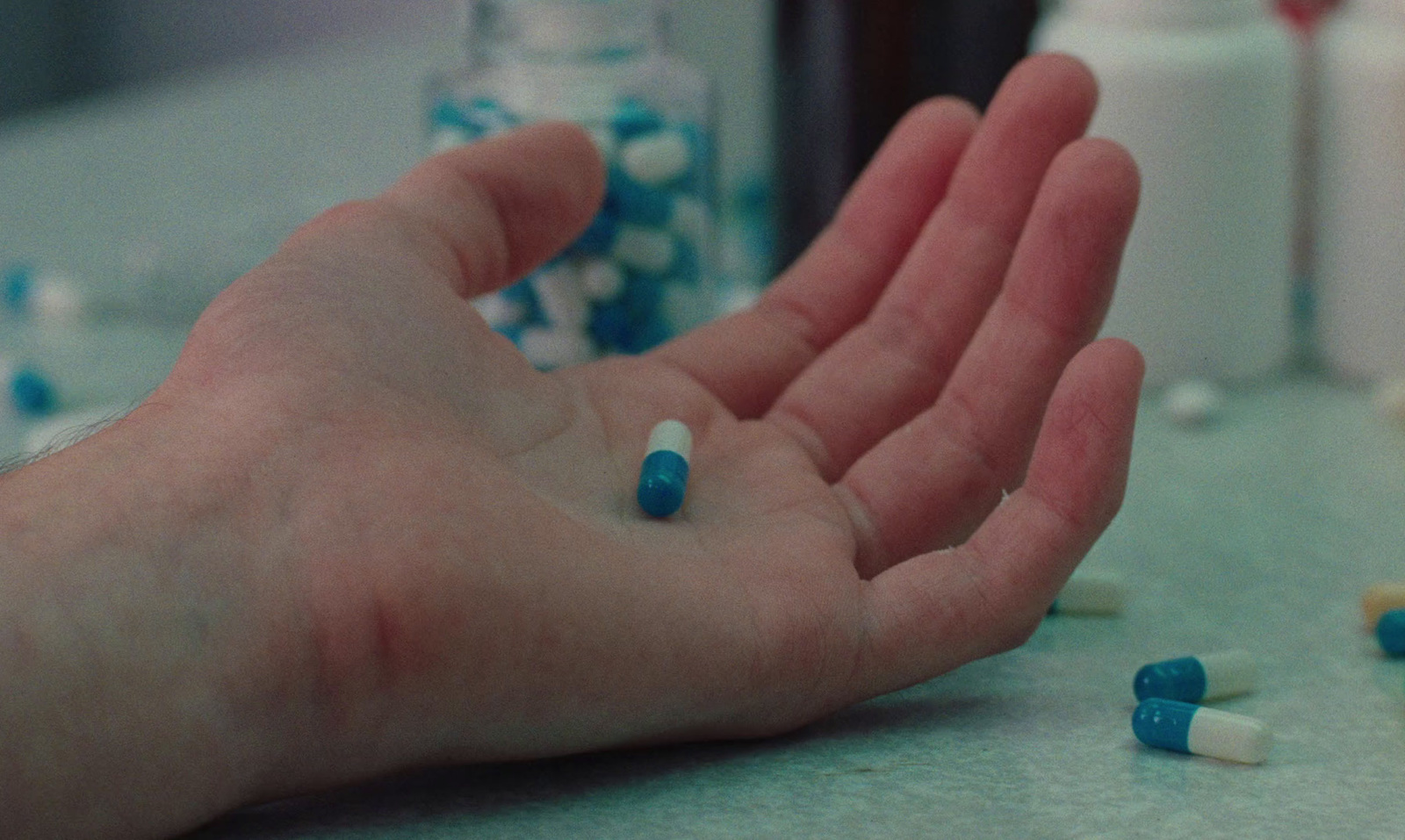 a person's hand with blue and white pills on it