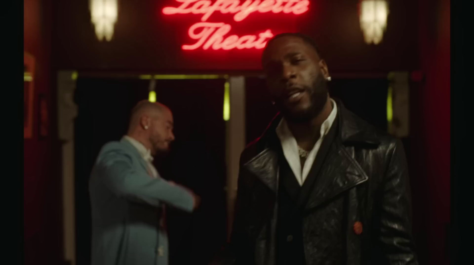 two men standing in front of a neon sign