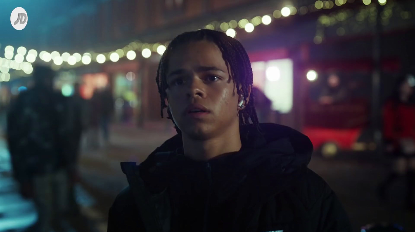 a man with dreadlocks standing on a street at night