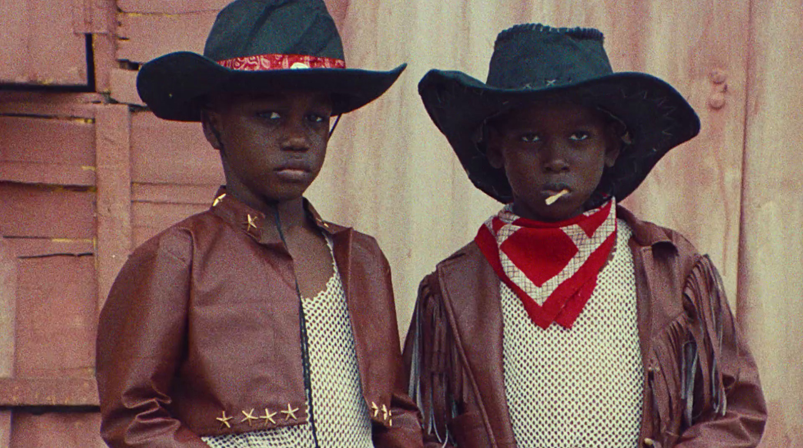 two young boys wearing hats and scarves standing next to each other